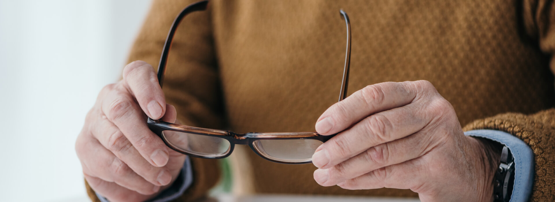 Adulto mayor toma unas gafas en sus manos