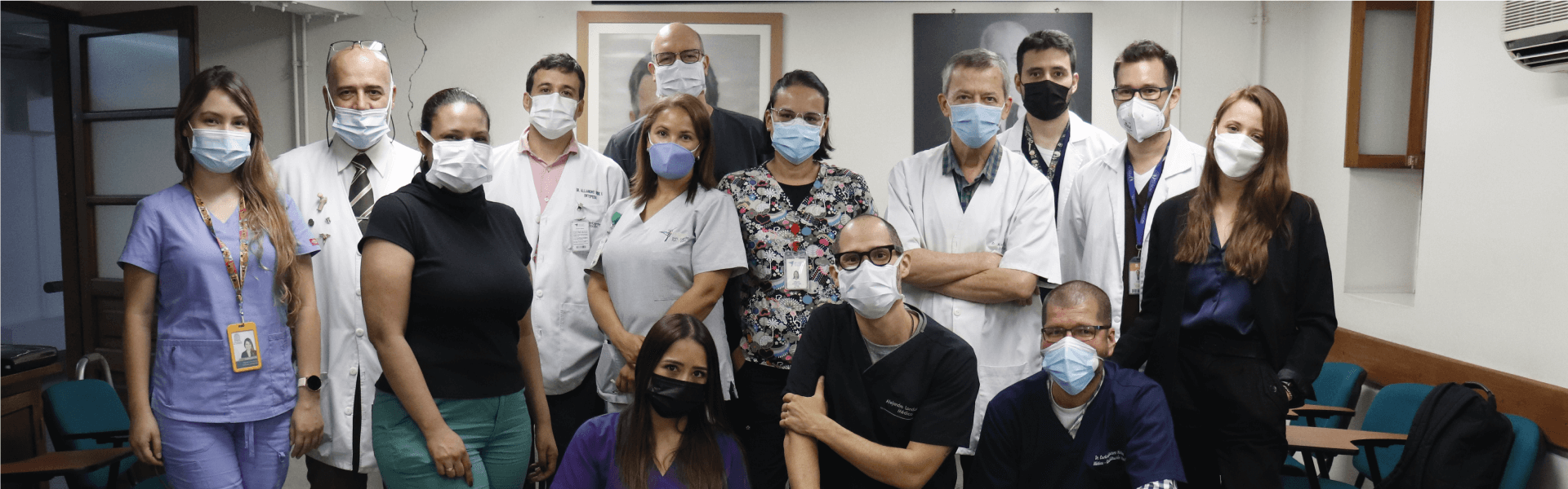 Grupo de personas reunidas en un cuarto de fondo blanco