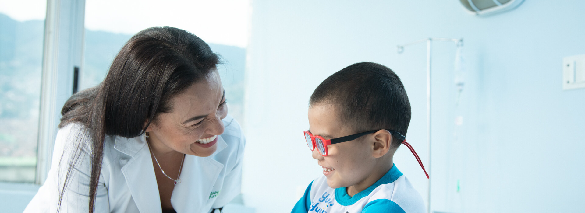 Doctora jugando con un niño con gafas rojas